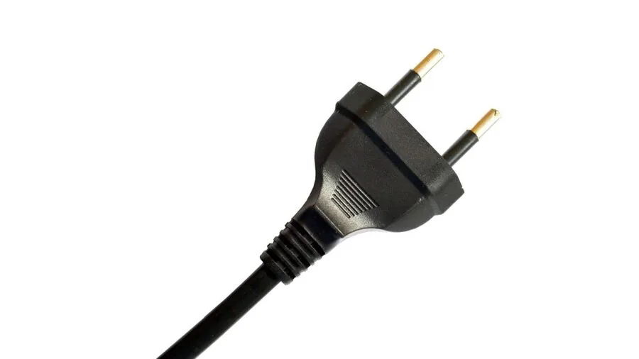 Person plugging electrical cord into wall outlet for home power charging