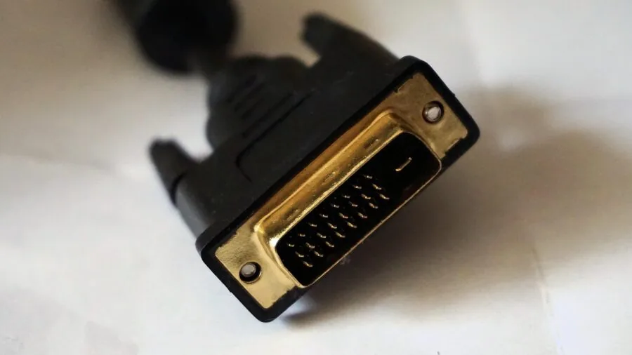 Person plugging HDMI cable into desktop computer monitor in home office workspace