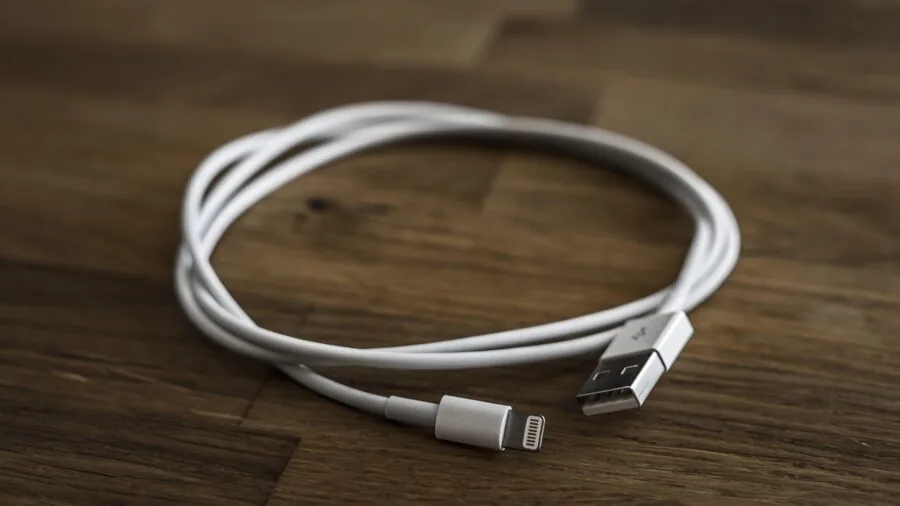 Person plugging multiple USB cables into ports at a home office desk setup