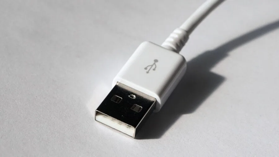 Person plugging USB cable into computer tower on desk setup