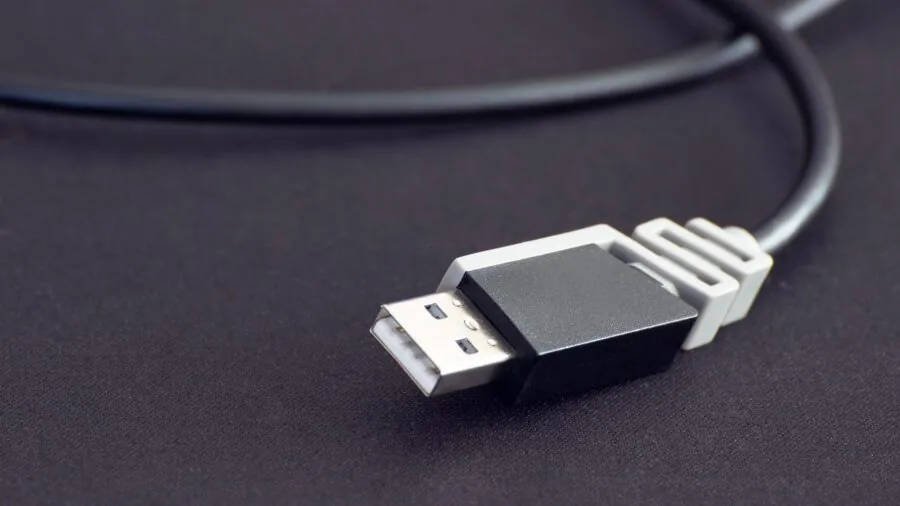Person plugging USB cable into laptop for device connectivity and setup