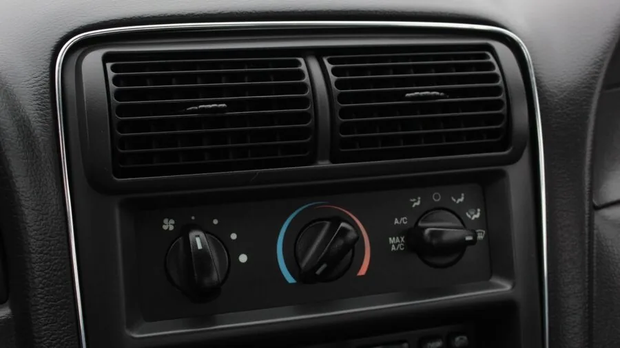 Person reaching toward wall-mounted thermostat to adjust home temperature settings
