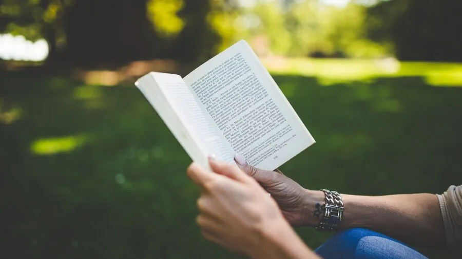 Person reading an e-reader outdoors in natural sunlight, demonstrating screen visibility and glare resistance