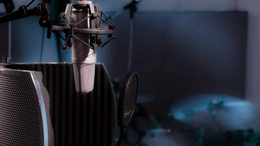 Person recording podcast in home studio setup with microphone and headphones