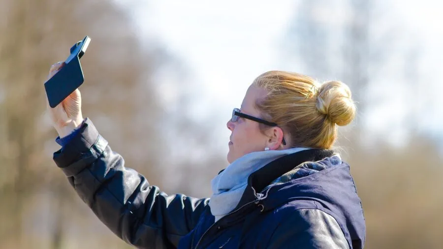 Person recording themselves with camera in landscape orientation during outdoor content creation