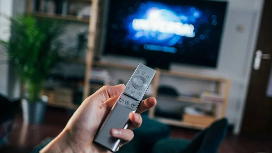 Person relaxing on couch watching TV in modern living room with natural lighting