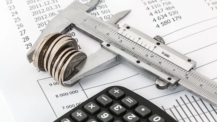 Person reviewing financial documents and calculating expenses with calculator and notebook on wooden desk