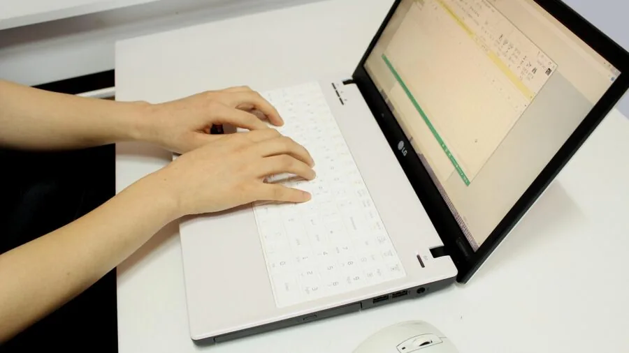 Person reviewing laptop warranty documentation and software guides at desk with coffee