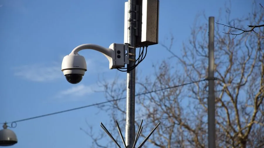 Person reviewing security camera footage on tablet outside residential home