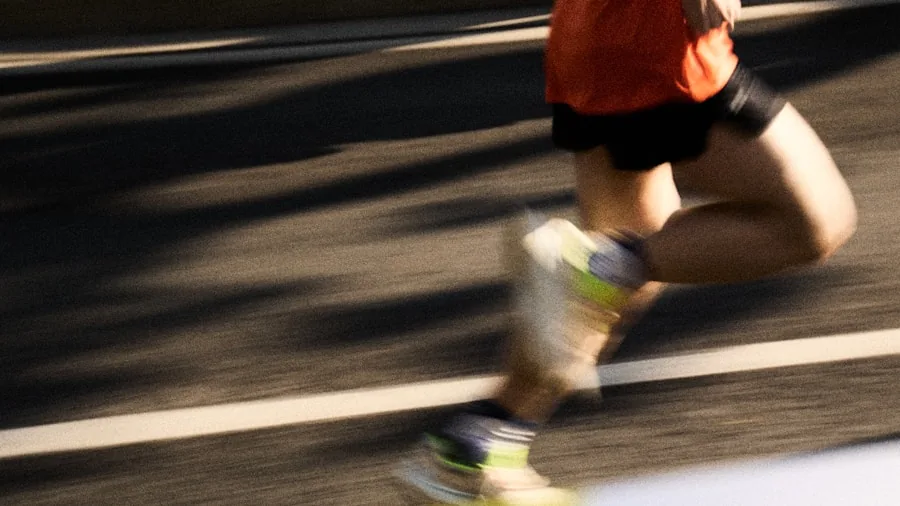 Person running outdoors on trail with focused expression during active workout