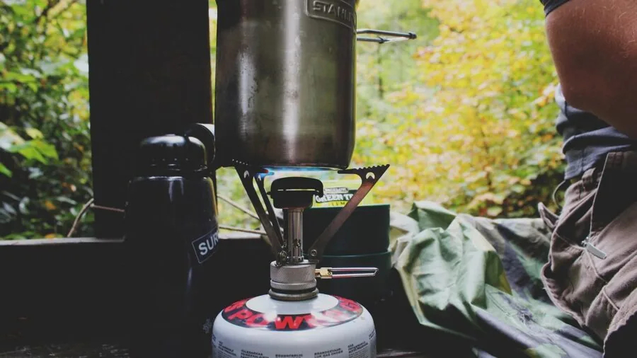 Person setting up a compact projector outdoors in a natural camping environment
