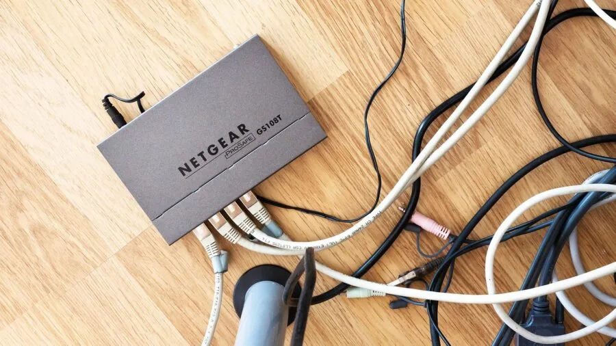Person setting up network infrastructure with cables in modern office workspace