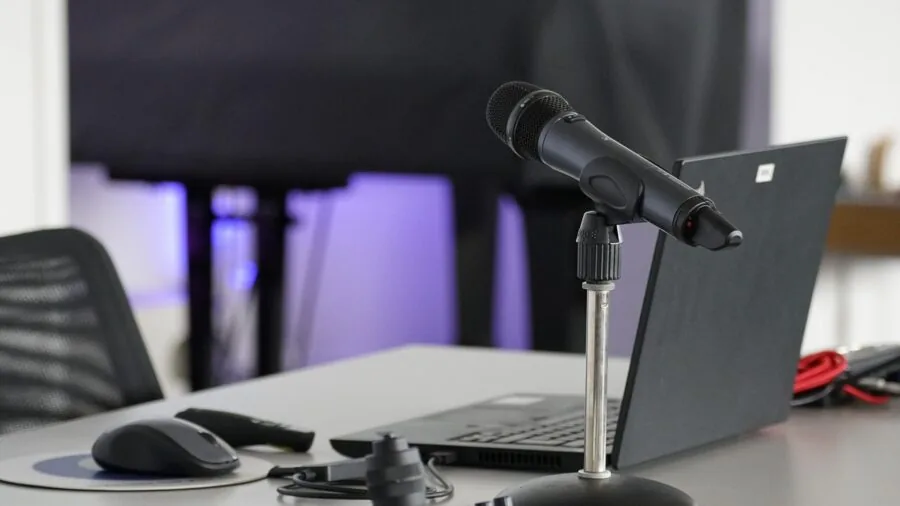 Person sitting at desk with microphone and headphones during online streaming or podcast recording session