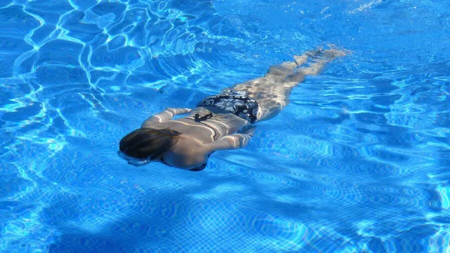Person swimming underwater in pool during workout session