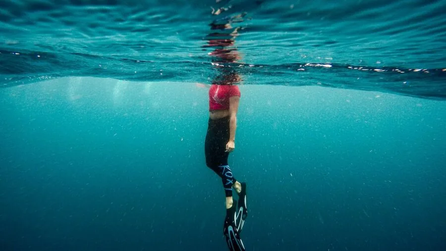 Person swimming underwater wearing a waterproof watch, demonstrating water resistance in a real aquatic environment