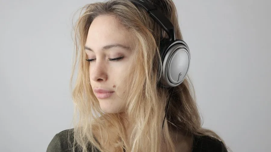 Person swimming underwater wearing open-ear headphones, listening to music while submerged in pool