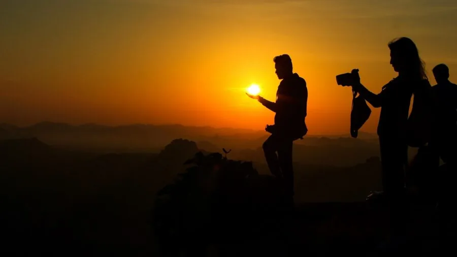 Person taking photos of scenic landscape during golden hour sunset with smartphone