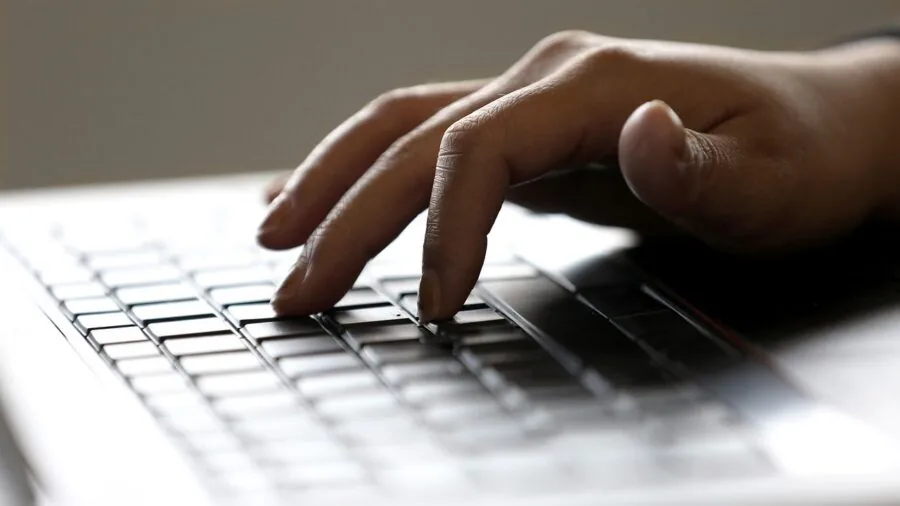 Person typing on keyboard at desk during work session, showing real-world keyboard usage and durability