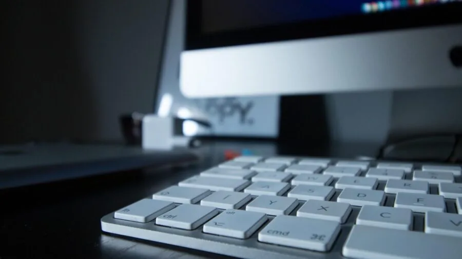 Person typing on keyboard at organized desk workspace with monitor and office supplies