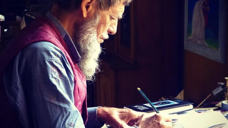 Person typing on keyboard at wooden desk in natural light, focused on work