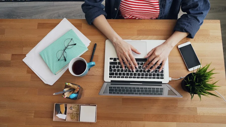Person typing on keyboard at wooden desk with natural lighting and coffee cup nearby