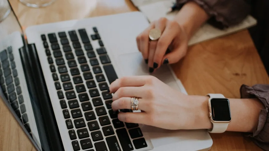 Person typing on laptop keyboard during extended work session at desk, focusing on hand position and typing comfort