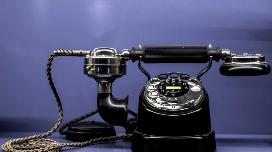 Person using landline telephone at home desk in modern living space