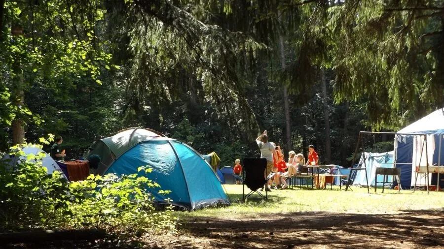 Person using portable power station to charge devices while camping in nature
