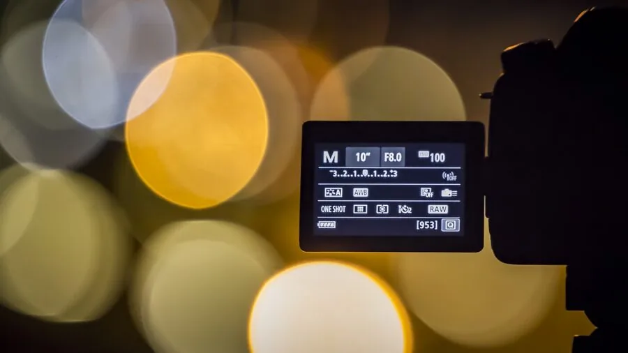 Person using smartphone to adjust camera settings and controls on streaming equipment during content creation