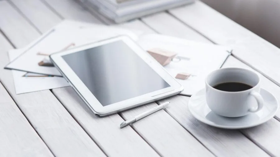 Person using stylus to write and take notes on digital tablet at desk