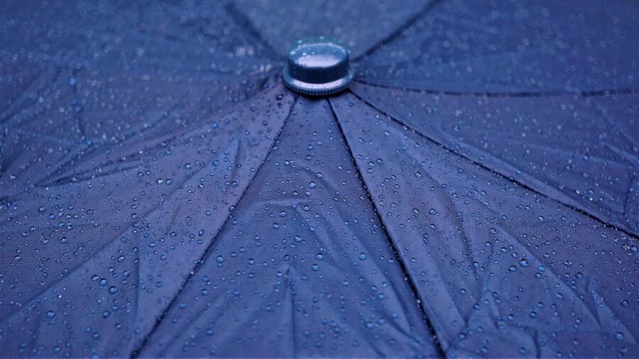 Person using water-resistant technology during outdoor activities in natural weather conditions