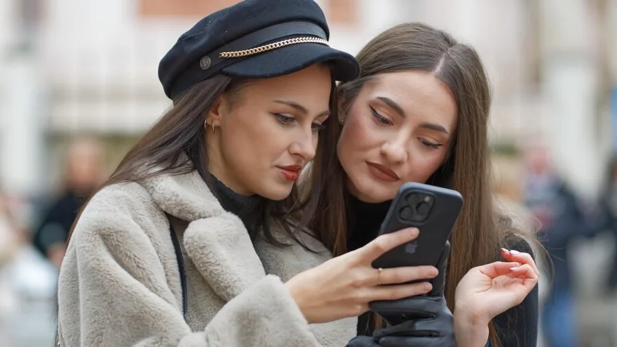 Person viewing health metrics and fitness data on smartphone while wearing smartwatch outdoors