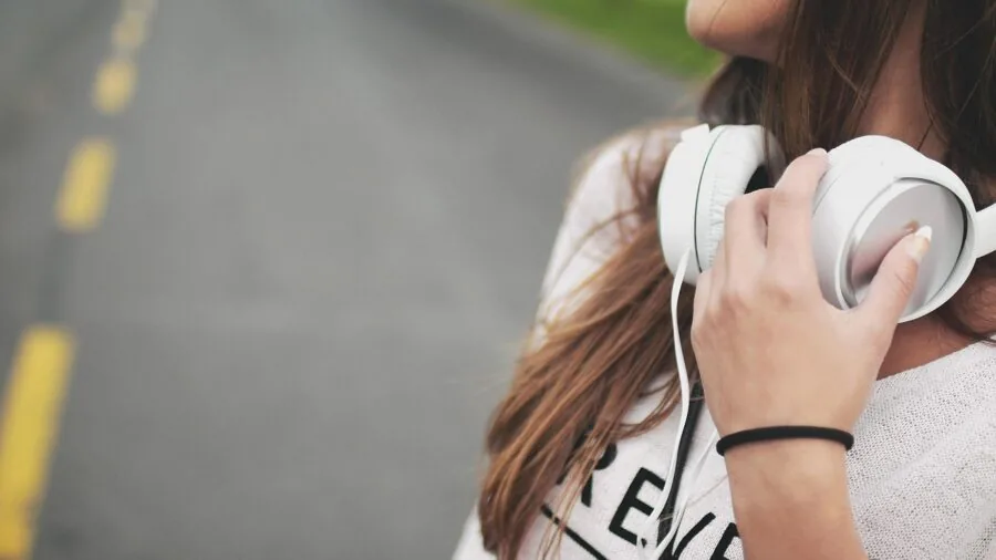 Person wearing earbuds enjoying high-quality audio while relaxing outdoors in natural sunlight