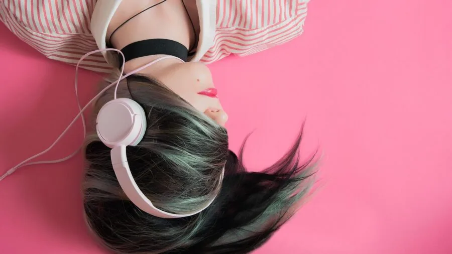 Person wearing earbuds on public transportation, focused on music with urban background noise around them