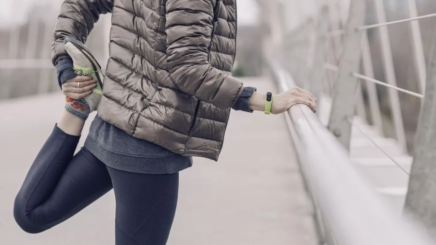 Person wearing fitness tracker checking stats while exercising outdoors in bright daylight