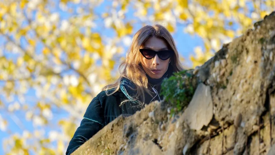 Person wearing glasses outdoors with open-ear audio experience in natural environment