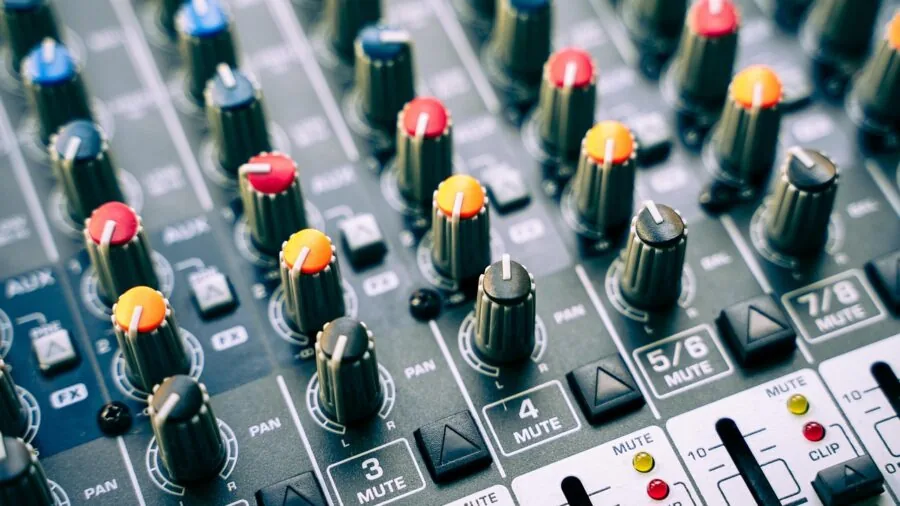 Person wearing headphones at a music production desk with audio equipment and monitors