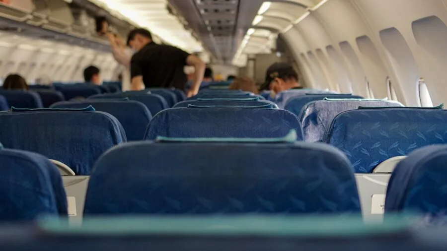 Person wearing headphones on an airplane, experiencing peaceful travel with noise isolation technology