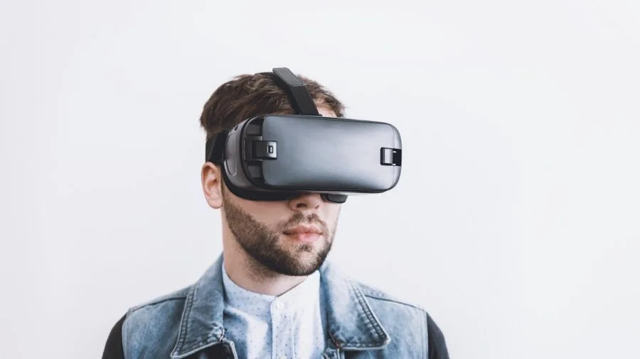 Person wearing VR headset playing immersive game in living room with hand controllers