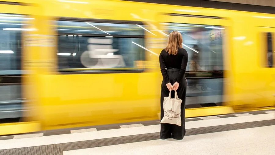 Person wearing wireless headphones during daily commute, checking battery life and charging considerations