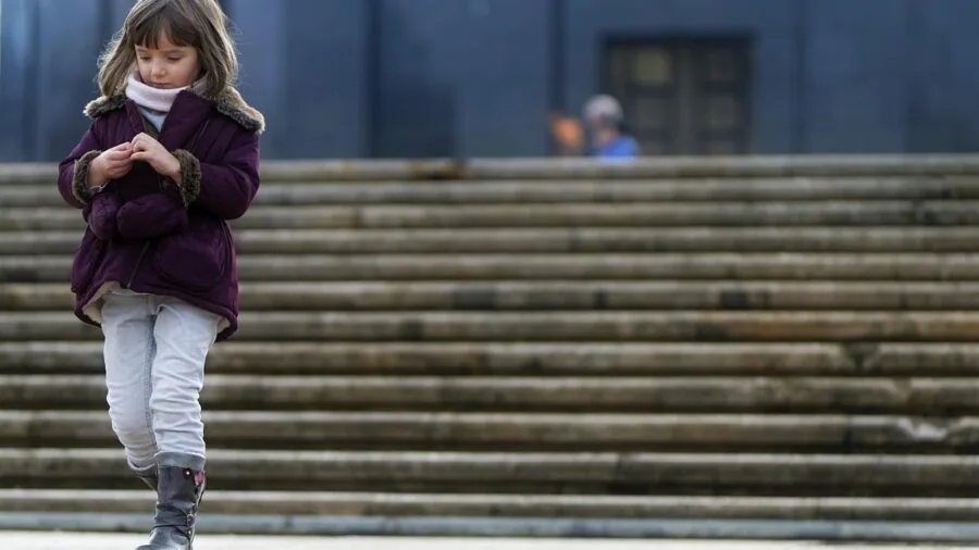 Person with small ears wearing wireless earbuds while listening to music outdoors