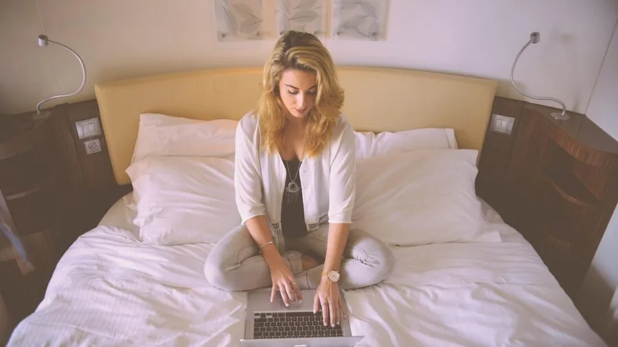 Person working at desk in home office with laptop and router setup