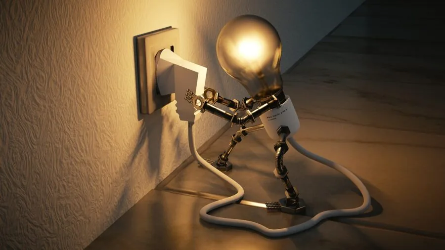 Person working at desk with computer setup and power cables, demonstrating home office energy usage
