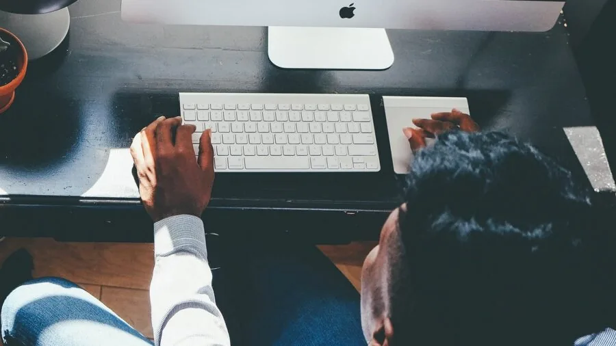 Person working at desk with laptop and external monitor in modern office workspace