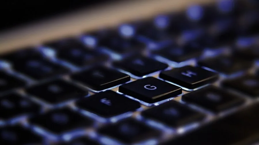 Person working at desk with mechanical keyboard and Mac computer in home office environment