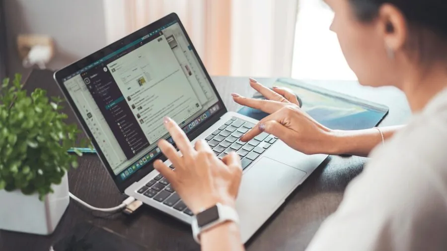 Person working at desk with multiple devices in modern home office setup
