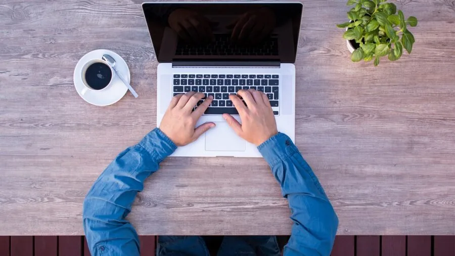Person working at desk with multiple monitors in home office setup with natural light