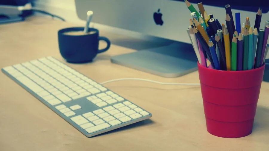 Person working at home office desk with keyboard and mouse setup in natural light