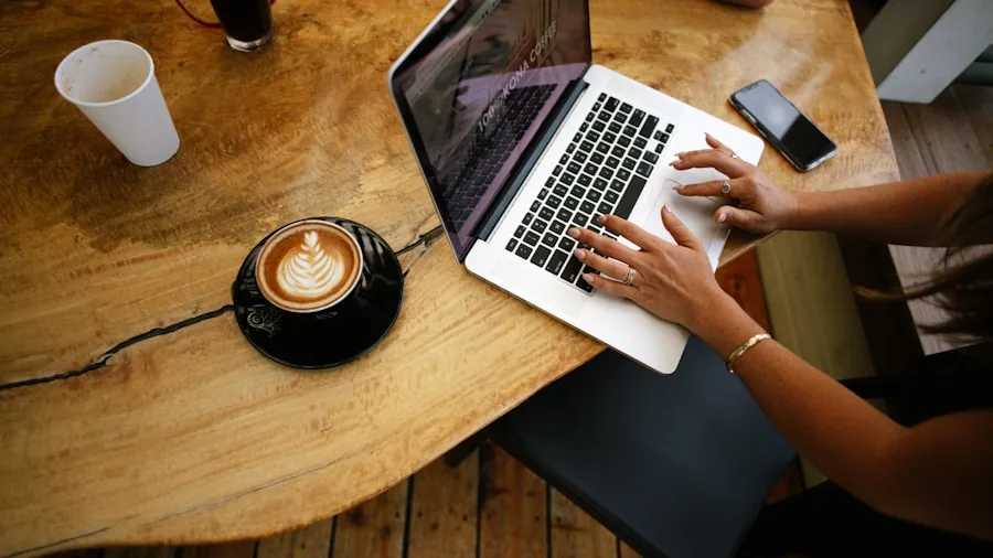 Person working on laptop at a cafe table with coffee, representing real-world portable computing scenarios