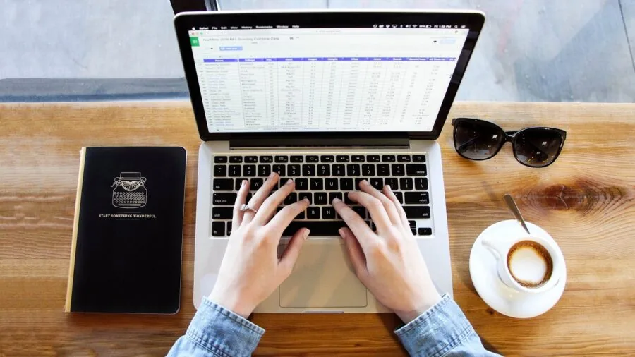 Person working on laptop at desk with low battery warning visible, illustrating real-world battery drain during work